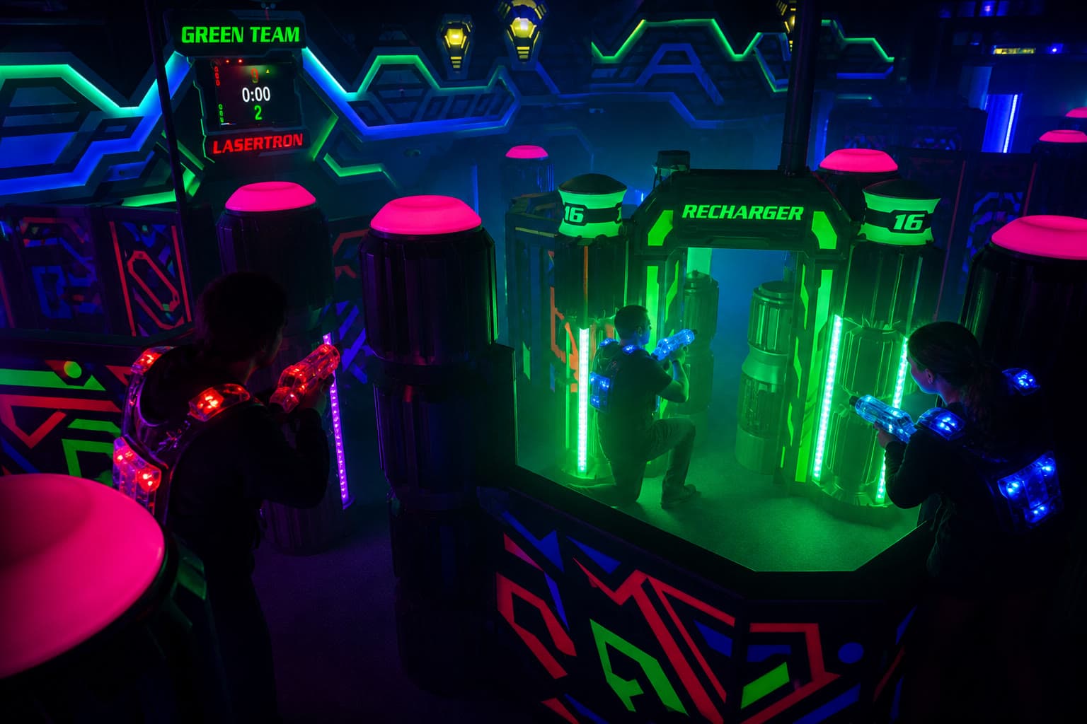 Players using cover near glowing recharger arches in the arena